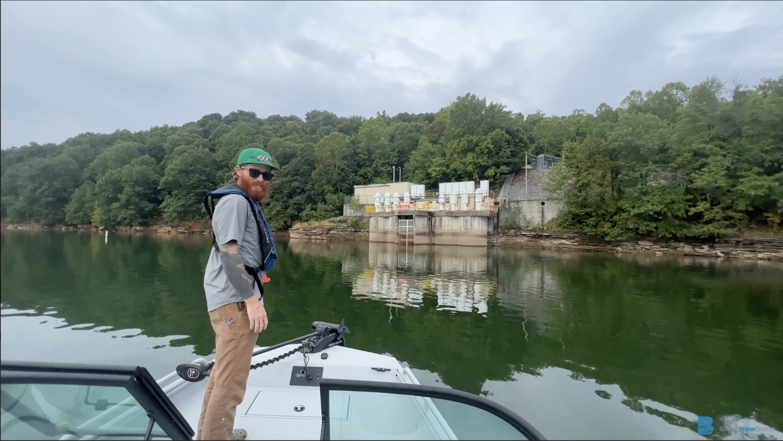 Man standing on a boat on Beaver Lake looking toward water treatment facility