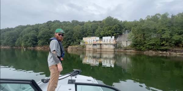 Man standing on a boat on Beaver Lake looking toward water treatment facility