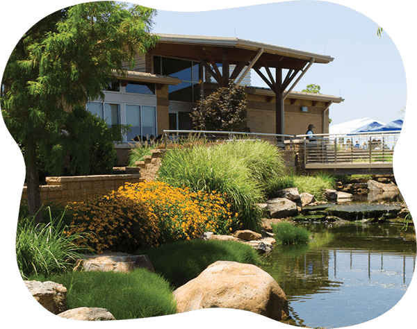 Beaver Water District Administration building surrounded by trees, bushes, and a pond.