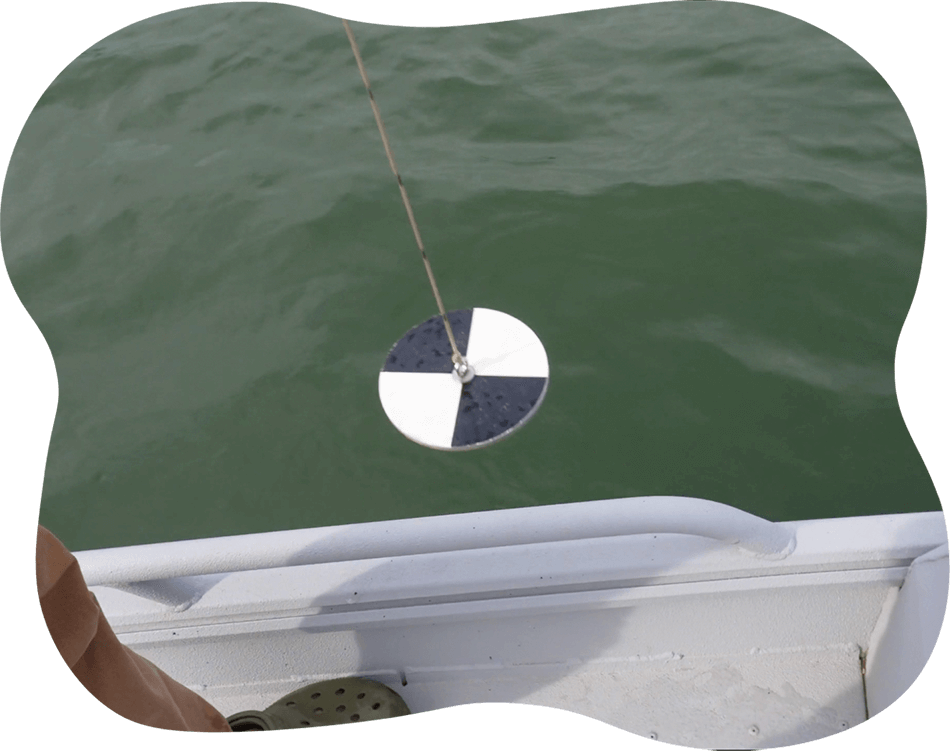 secchi-day Black and white round disk being lowered from a boat into lake water